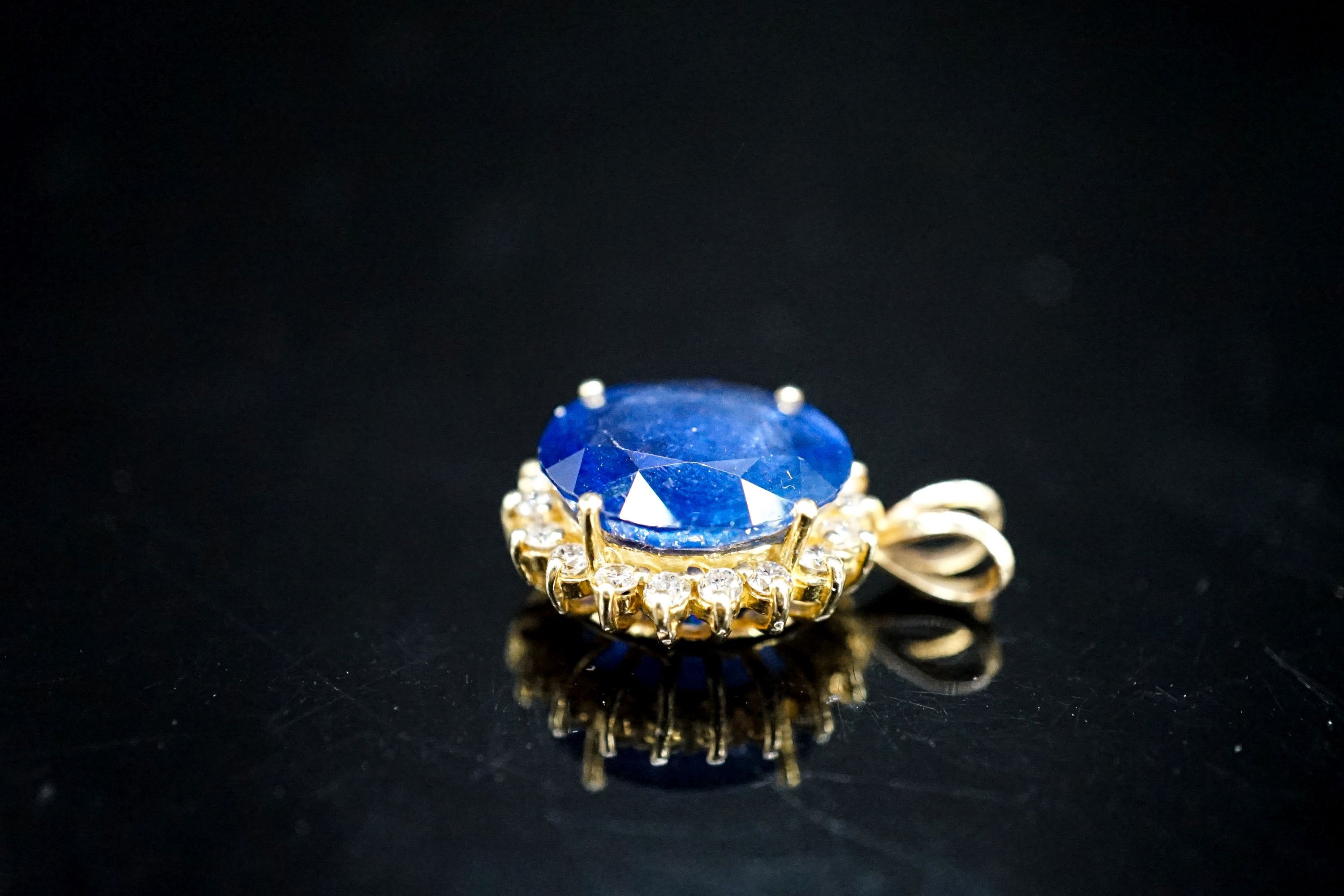 A yellow metal mounted sapphire and diamond set oval cluster pendant, 23mm, gross 4.6 grams.